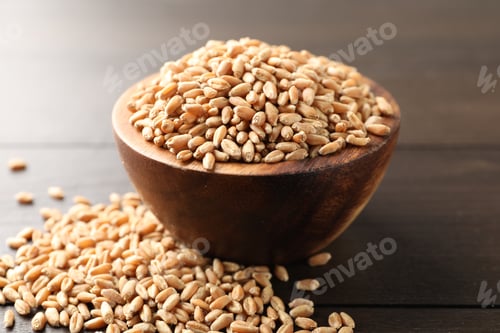 Preview: Wheat grains in bowl on wooden table, closeup