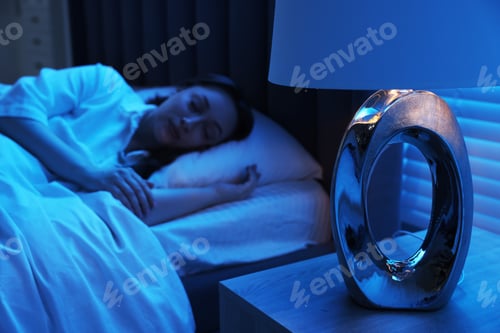 Preview: Woman sleeping with illuminated night lamp at home, selective focus