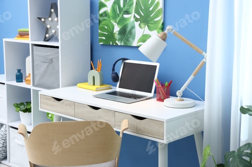 Preview: Stylish workplace with laptop, headphones and stationery in child's room