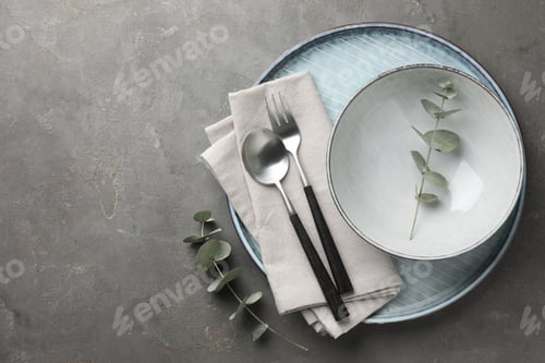 Preview: Stylish setting with cutlery, napkin, eucalyptus branches and plate on grey table, top view. Space f