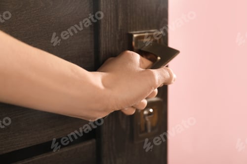 Preview: Woman opening wooden door with key indoors, closeup