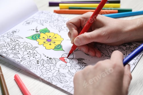 Preview: Woman coloring antistress picture with felt tip pen at white wooden table, closeup