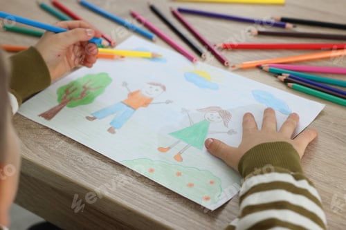 Preview: Little boy drawing with pencil at wooden table, closeup