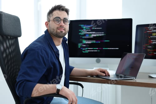Preview: Young programmer working at desk in office