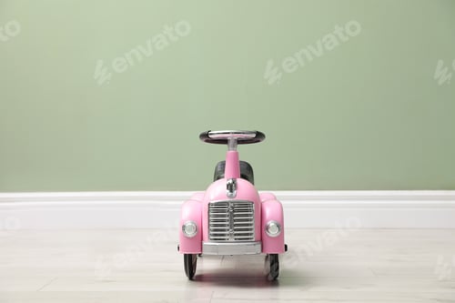 Preview: Pink toy car near light green wall indoors