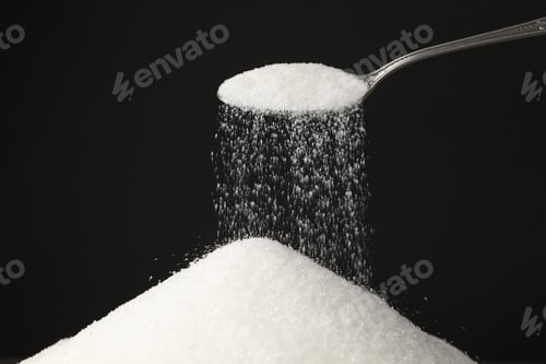 Preview: Pouring granulated sugar onto pile against black background, closeup