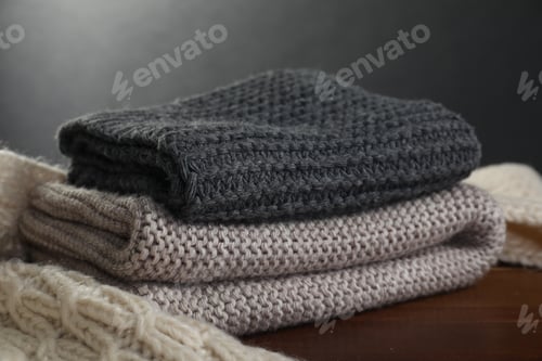 Preview: Knitted scarfs on wooden table against gray background, closeup