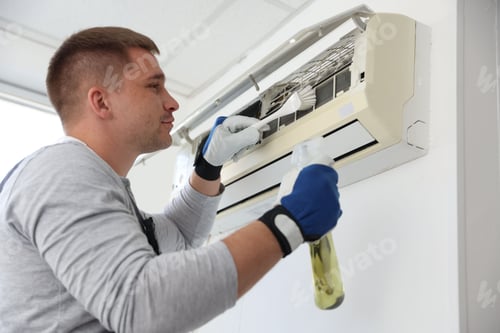 Preview: Man cleaning air conditioner with brush and spray indoors