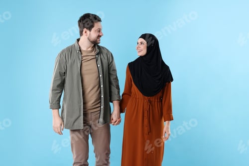 Preview: Portrait of happy muslim couple on light blue background