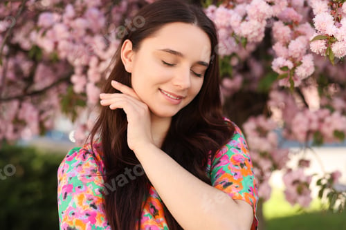 Preview: Beautiful woman near blossoming tree on spring day