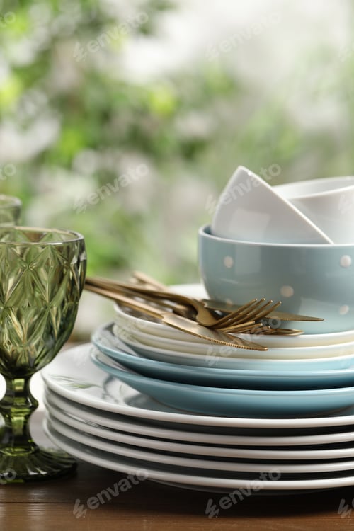 Preview: Beautiful ceramic dishware, glass and cutlery on wooden table outdoors