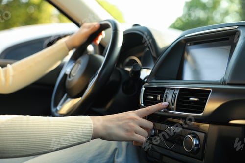 Preview: Woman turning on hazard lights while driving modern car, closeup