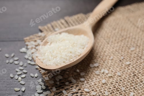 Preview: Raw rice in spoon and burlap fabric on wooden table, closeup