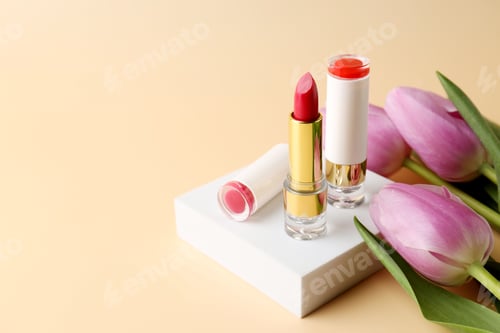 Preview: Lipsticks and flowers on beige background, closeup. Space for text