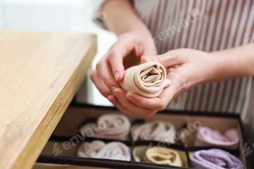 Preview: Woman putting socks into drawer with organizer indoors, closeup