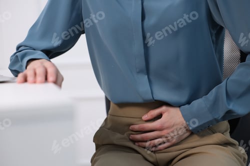 Preview: Woman suffering from menstrual pain at workplace, closeup