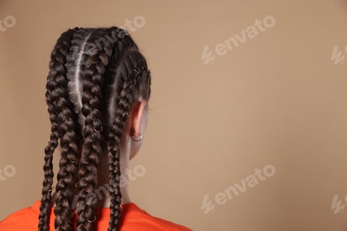 Preview: Teenage girl with beautiful braids on beige background, back view. Space for text