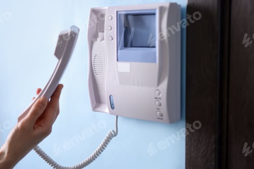Preview: Woman answering intercom call at home, closeup