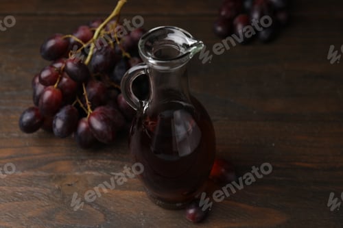 Preview: Jug with wine vinegar and grapes on wooden table, closeup