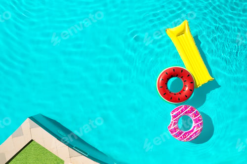 Preview: Inflatable rings and mattress floating in swimming pool, top view