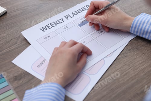 Preview: Woman with weekly planner at wooden desk, closeup