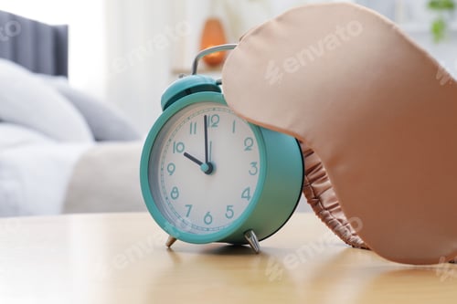 Preview: Alarm clock and sleeping mask on wooden table in bedroom, closeup. Space for text