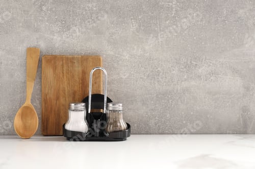 Preview: Cutting board, spoon and spices on white table near grey wall. Space for text