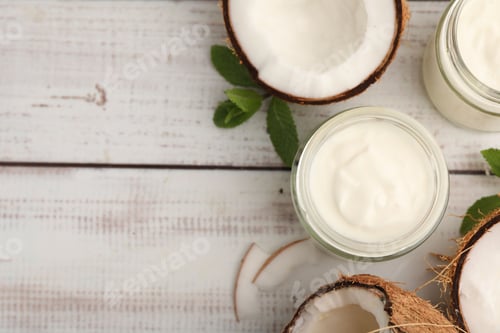 Preview: Delicious coconut yogurt in glass jars, mint leaves and fruits on white wooden table, flat lay. Spac