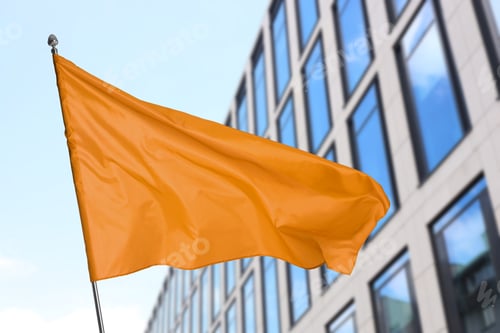 Preview: Bright orange flag waving on city street
