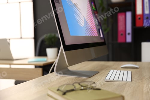 Preview: Computer, glasses and notebook on wooden desk in office, closeup