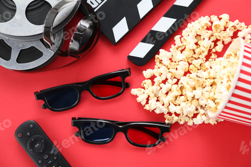 Preview: 3D glasses, tasty popcorn, remote control, clapboard and film reels on red background, flat lay