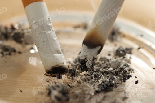 Preview: Cigarette butts smoldering in ashtray on table, closeup
