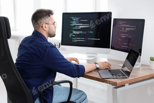 Preview: Young programmer working at desk in office