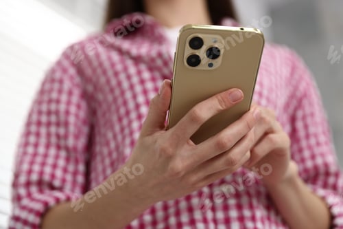 Preview: Woman sending text message via smartphone indoors, low angle view