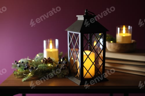 Preview: Christmas lantern, burning candles, books and decor on wooden table against dark pink background, cl