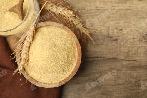 Preview: Raw semolina in bowl with spikes on wooden table, flat lay. Space for text