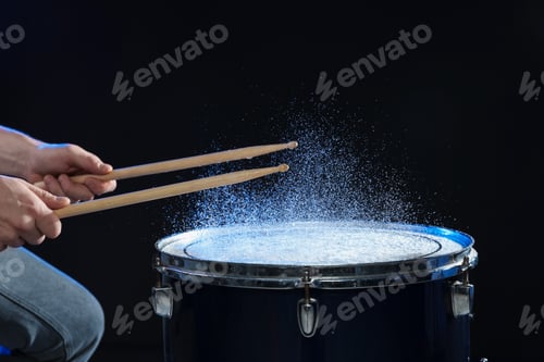 Preview: Man with drumsticks playing drum on black background, closeup
