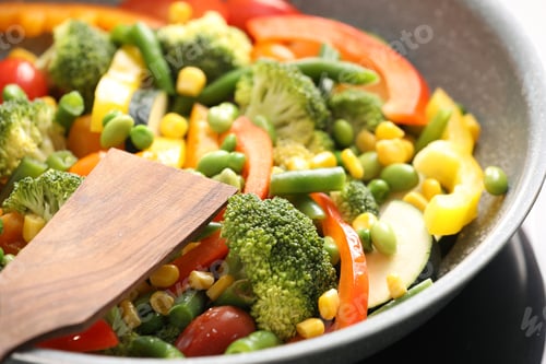 Preview: Different vegetables and spatula in frying pan on stove indoors, closeup
