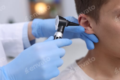 Preview: Hearing test. Doctor examining man's ear with otoscope in clinic, closeup