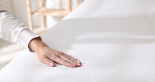 Preview: Woman touching soft mattress on bed indoors, closeup