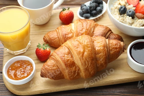 Preview: Healthy breakfast. Tasty croissants, jams, oatmeal with berries, orange juice and coffee on wooden t