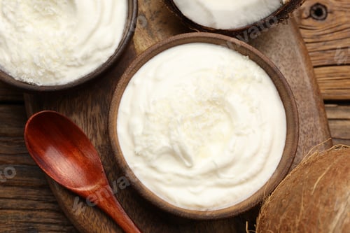 Preview: Tasty coconut yogurt with flakes on wooden table, flat lay