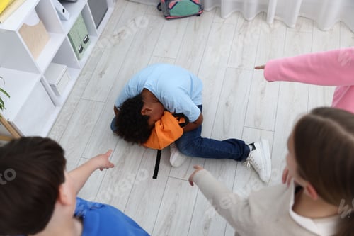 Preview: African American boy getting bullied by his classmates in classroom, above view