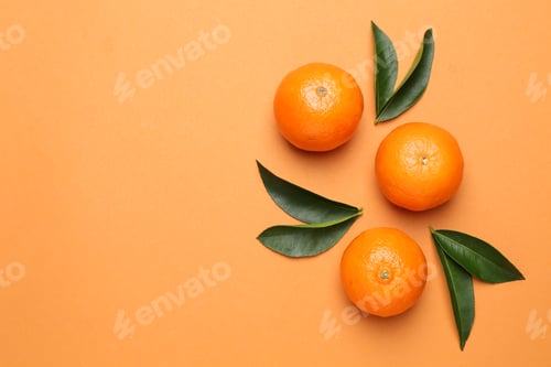 Preview: Fresh ripe tangerines and leaves on orange background, flat lay. Space for text