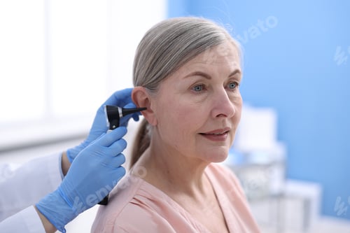 Preview: Hearing test. Doctor examining woman's ear with otoscope in clinic, closeup