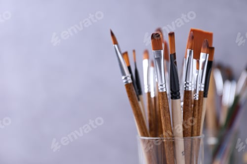 Preview: Paint brushes in glass on blurred background, closeup. Space for text