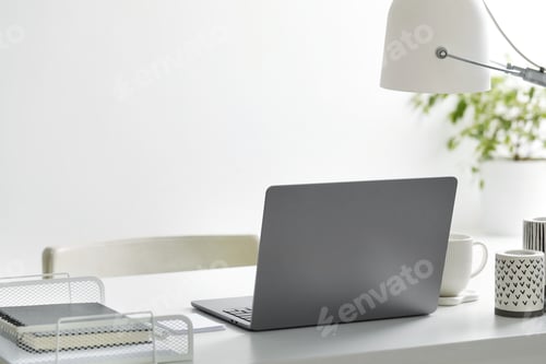 Preview: Stylish workplace with laptop, stationery, candles, cup and lamp indoors
