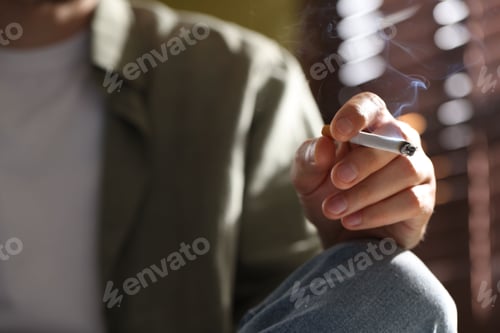 Preview: Man smoking cigarette at home, closeup. Bad habit