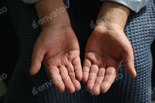 Preview: Elderly man covering with blue blanket holding something, top view