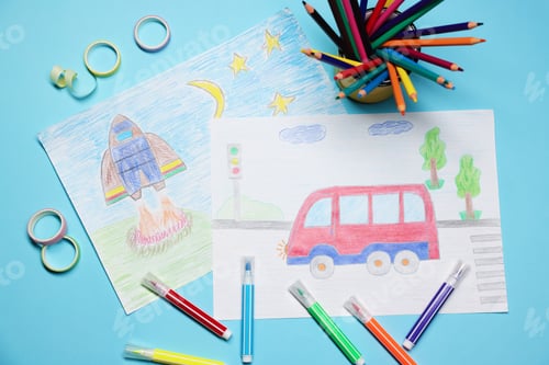 Preview: Child's drawings, felt-tip pens and pencils on light blue background, flat lay